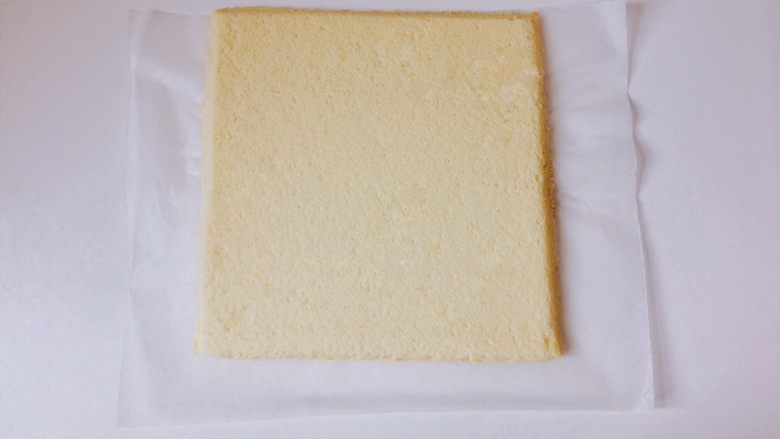 奥利奥咸奶油蛋糕卷,将烤盘倒扣,小心撕掉原来那张油布(油纸),在蛋糕上盖上一层保鲜膜,确保蛋糕体水分不会流失,然后晾凉,斜切掉边缘。