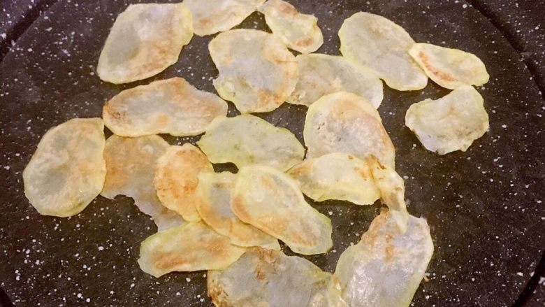 平底锅版健康无油香脆薯片,两面全部呈金黄色后,再用筷子将土豆片聚拢在锅中间,继续烘三十秒左右,期间用筷子扒拉扒拉,注意不要烘焦了