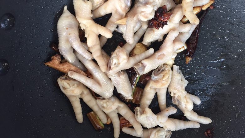 红烧鸡爪,锅里的香料炒出香味后,转中火,放入刚才焯水的鸡爪,快速翻炒。