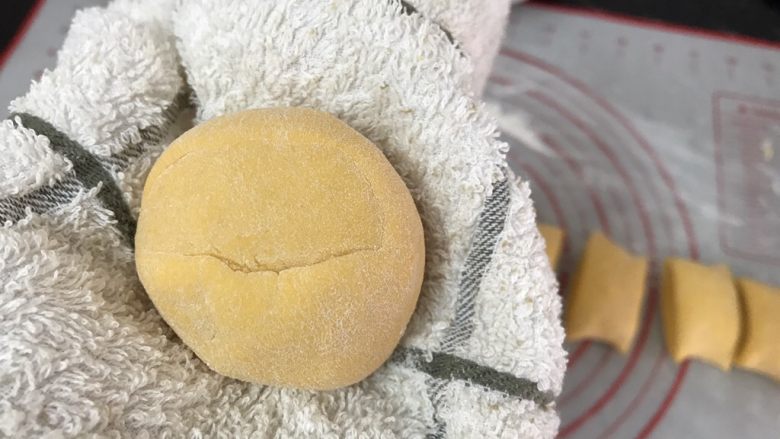 以假乱真~橘子馒头,拿起一块先搓圆,表面均匀沾一层面粉,放在一张干净的毛巾上