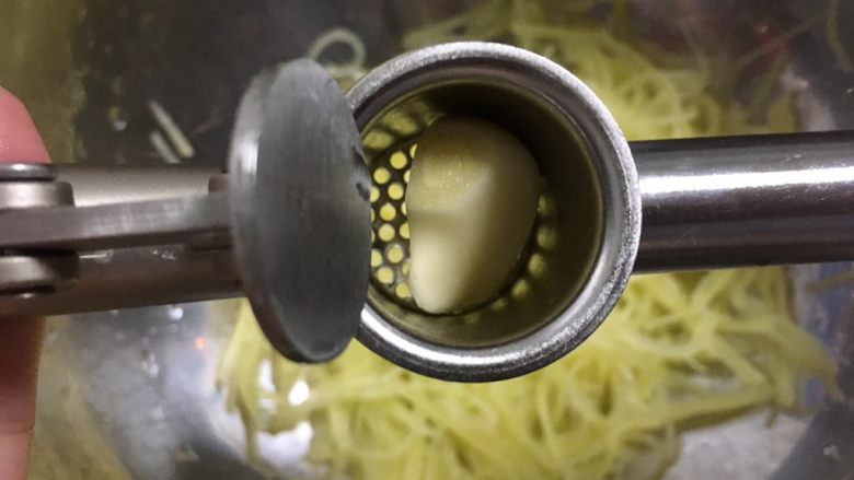 炝拌土豆丝,捞出沥干水分放深容器中,在上面夹两瓣蒜蓉