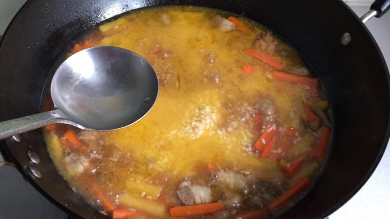 新疆碎肉抓饭,再撒上大米,葡萄干,用勺背把大米推平,水面高出大米1公分;
