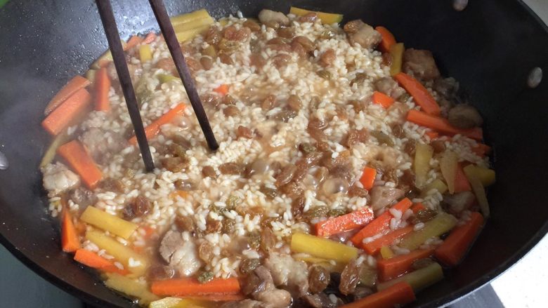 新疆碎肉抓饭,大约20分钟,水分快干时,筷子插入锅里,使抓饭的热气上升,水分下沉;