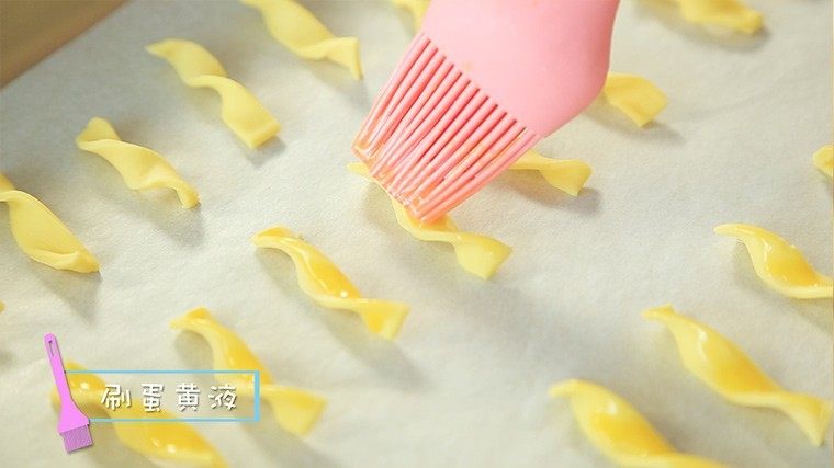 橙汁磨牙棒,烤盘垫上硅油纸,把螺旋长条按照顺序放在烤盘上,刷上蛋黄液。