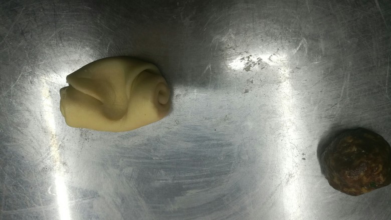 超级好吃的鲜肉月饼,把面团拿出来,中间按一下,两边往中间收,擀开,把肉馅放在中间,尽量擀大一点,然后收口,一定不要有漏的地方,否则烤的时候会漏油,把收口朝下放
