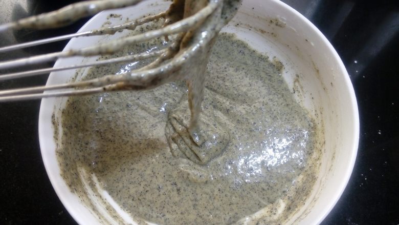 龙猫黑芝麻戚风,拌好的蛋黄糊应该是细腻有光泽的。提起手抽,蛋黄糊能呈绸带状落下为最佳状态。