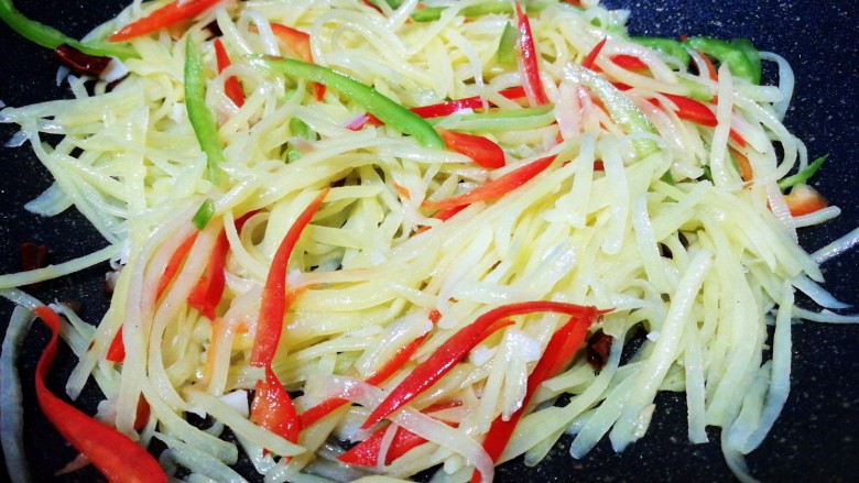 酸辣土豆丝,放入盐调味，放入红，青椒丝炒匀