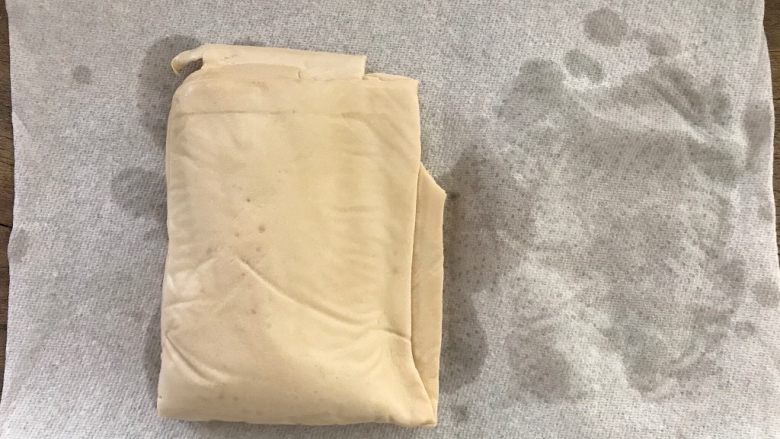 雪菜毛豆炒厚百叶,接下来,我们拿出浸泡在清水里的厚百叶,用厨房纸轻轻地吸干水分