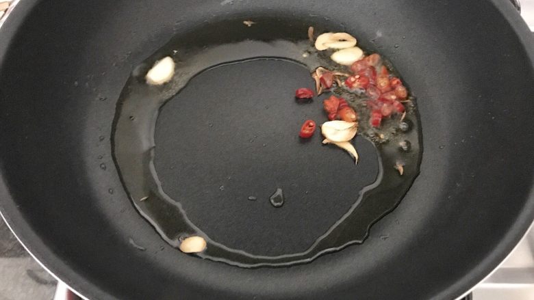 雪菜毛豆炒厚百叶,当油锅有7、8分热,开中小火将朝天椒和大蒜加进来