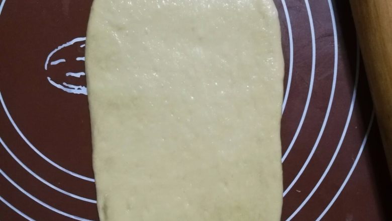 奶茶吐司(一次发酵),10.取一块面团擀成牛舌状,卷起来,再擀成牛舌状,再卷起来。