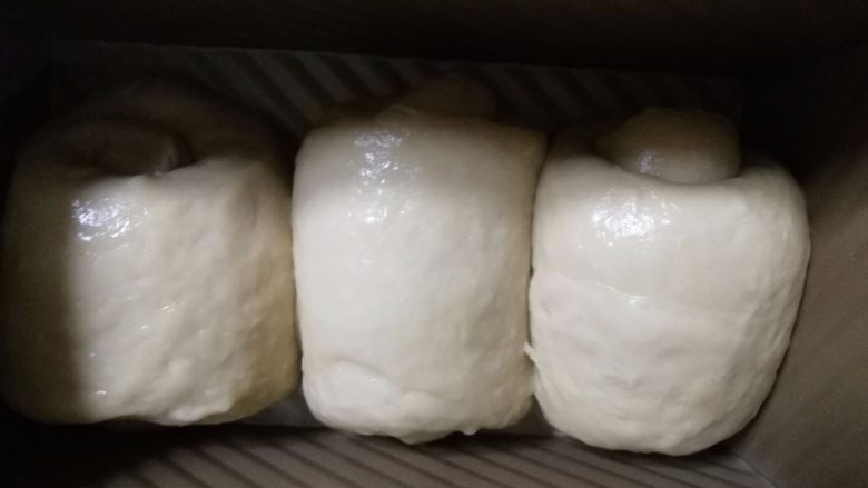 奶茶吐司(一次发酵),11.卷好的面团放在吐司盒中。放在温暖湿润的地方发酵。