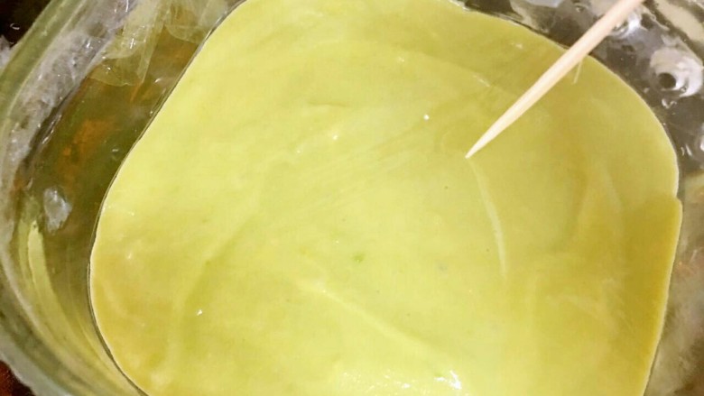 牛油果泥鸡蛋蒸糕,把搅拌均匀的果泥倒入碗中扶平,用牙签在上面扎少许透气孔