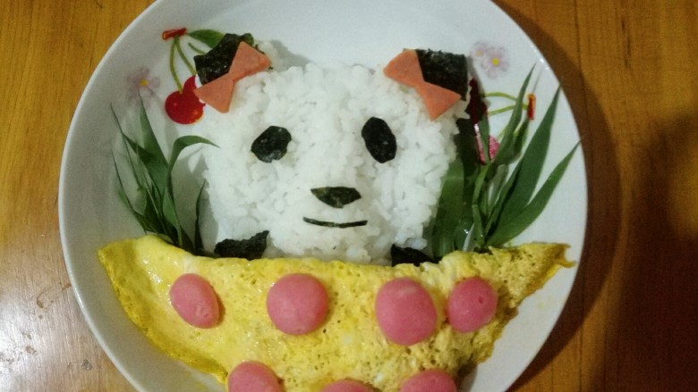 大熊猫饭团,煎好的鸡蛋对半折,盖住熊猫的身体,鱼卷挨个摆在鸡蛋上