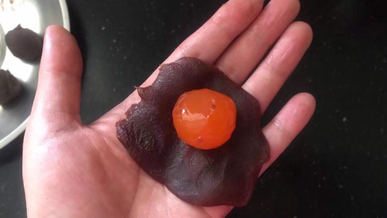 蛋黄酥,取一份红豆沙拍扁,放入一个咸蛋黄。