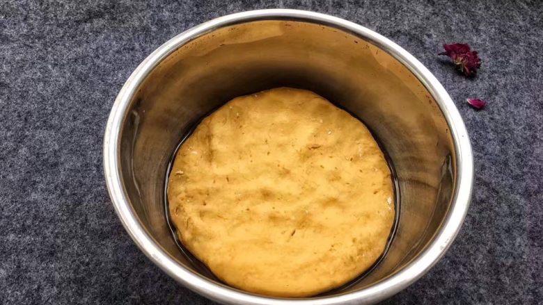 南瓜发糕,盆底刷上一层油,南瓜面团压扁。