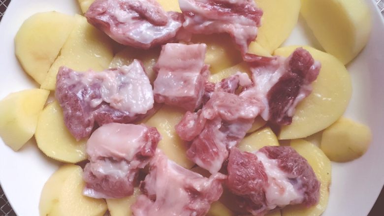 土豆蒸排骨,把腌制好的排骨铺在土豆块上,在排骨上浇点油,不需要太多,因为排骨上也会有油。