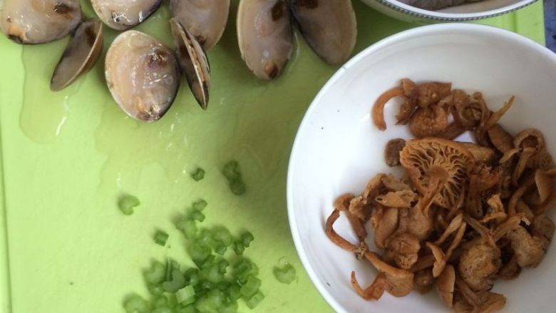 文蛤虾仁海鲜粥,将文蛤对半切开(我的文蛤是放冰箱冷冻的所以需要切开,如果是新鲜的文蛤可忽略这一步),芹菜切小丁,姜切丝,鸡针菇泡开,备用。