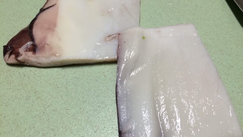 爆炒香辣鱿鱼翅,首先取一块鱿鱼翅横切,片成两片,因为鱿鱼翅比较厚,所以需要片薄一点,切成细条
