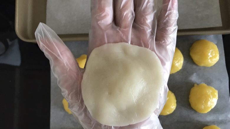 奶黄冰皮月饼,将冰皮压扁成中间厚周围薄的圆片,包上奶黄馅