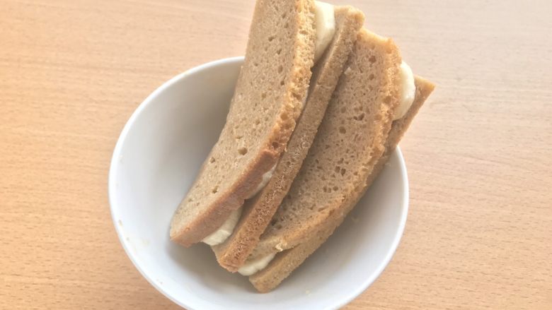 香蕉派(全麦吐司版),将另一侧轻轻压到摆着香蕉片的一侧,形成“卷”。然后沾上剩余蛋液,放一旁待用。
