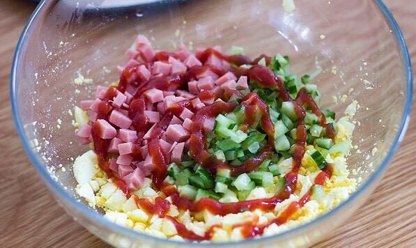 快手美味鸡蛋三明治,鸡蛋碎，黄瓜丁，火腿丁混合，再加入适量食盐和番茄酱，顺时针搅拌均匀