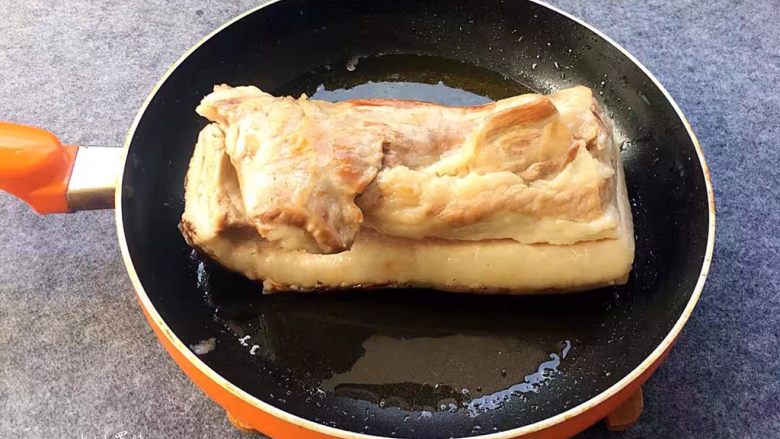 梅菜扣肉,锅中烧油,油温烧到六成热时,放猪肉入锅煎炸,注意煎炸的时候肉皮朝下,炸到肉皮皱起,变成金黄色后捞出,控油后待肉皮放凉回软,接着用刀切成筷子厚的长条。
