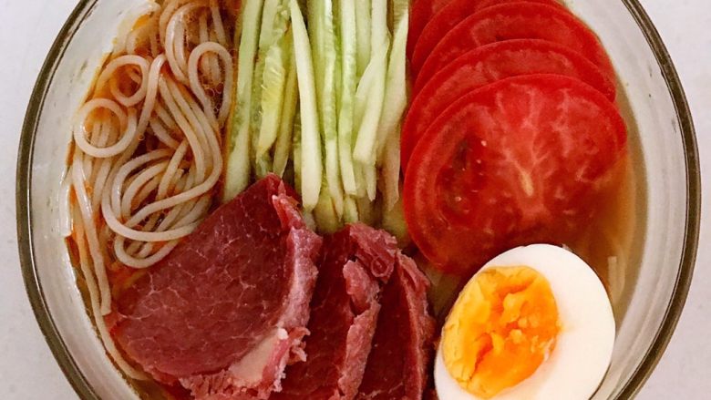 捞汁莜面,在泡好的一莜面上放入瓜丝,牛肉,西红柿勺,熟鸡蛋,浇上调好的汤汁