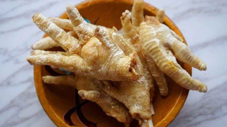 花生凤爪,3.锅内倒油烧热将凤爪炸至表面起泡变皱捞出沥干油待用