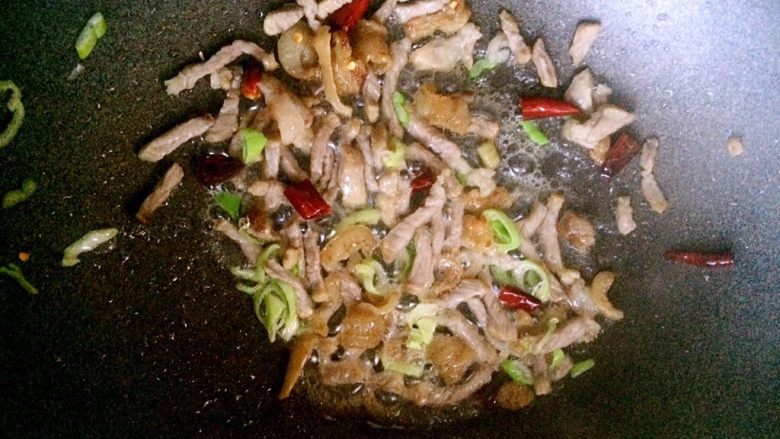 肉沫酸豆角,锅内放油烧热,放干辣椒小火炒香。放肉末,葱花爆炒。