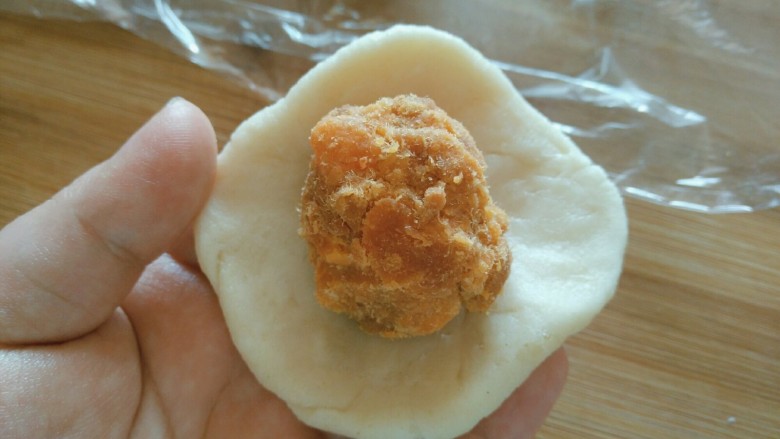 蛋黄肉松小酥饼,蛋黄馅儿放在油酥皮上，收紧口，收口朝下放置。