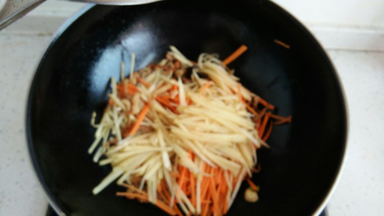 肉炒三丝,放入胡萝卜丝,土豆丝翻炒,加入半勺水,继续翻炒