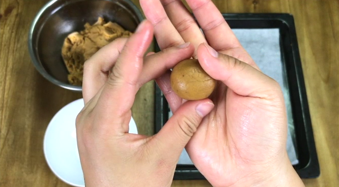 M&M豆花生饼干,将面团在掌心里揉成小球。在细砂糖里滚一遍,让表面沾满糖。