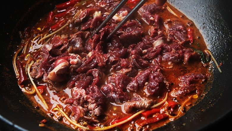 麻辣滑嫩的水煮牛肉,把牛肉倒入锅内划散,烫至肉片变色后立刻捞起放入装着豆芽和油麦菜的碗中;
