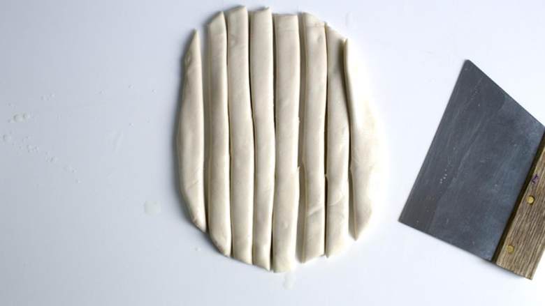 辣味孜然羊肉配手擀面,准备一小杯芥花油。手上抹油，把面团转移到抹了油的表面上，擀开成1厘米厚的长方形面片，再切成10根长条。