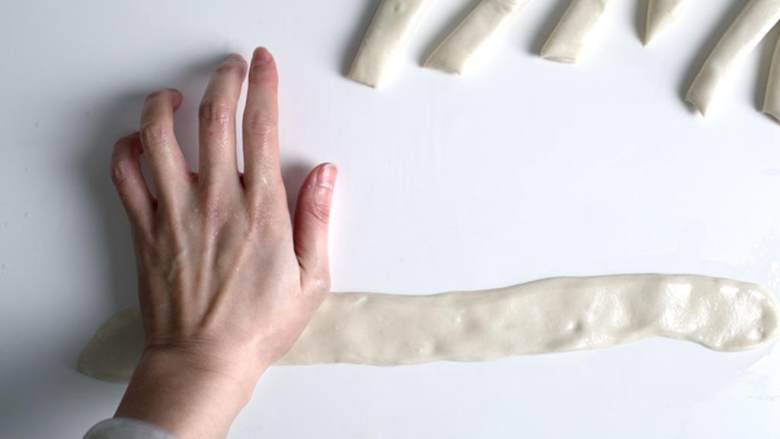 辣味孜然羊肉配手擀面,取一个面条，与案板上轻轻压扁，然后用手掌往外推，压成又长又宽的扁面条。不要担心压不均匀或者没有形成直角，这都不要紧。