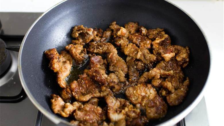 辣味孜然羊肉配手擀面,煮一大锅水，同时，加热一个深型的大号平底锅/炒锅，开大火；在腌好的羊肉中加入芥花油 ，把羊肉分开，然后倒入热好的锅中，尽可能地铺开。