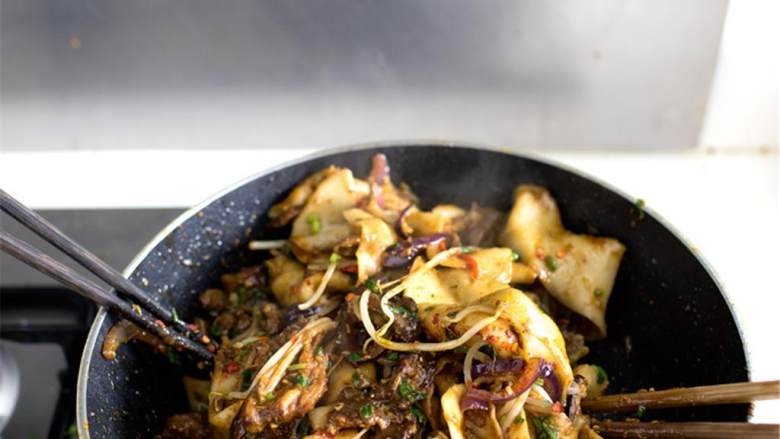 辣味孜然羊肉配手擀面,转为大火，加入羊肉和洋葱，把所有的食材拌匀，再加入最后一碗香草。