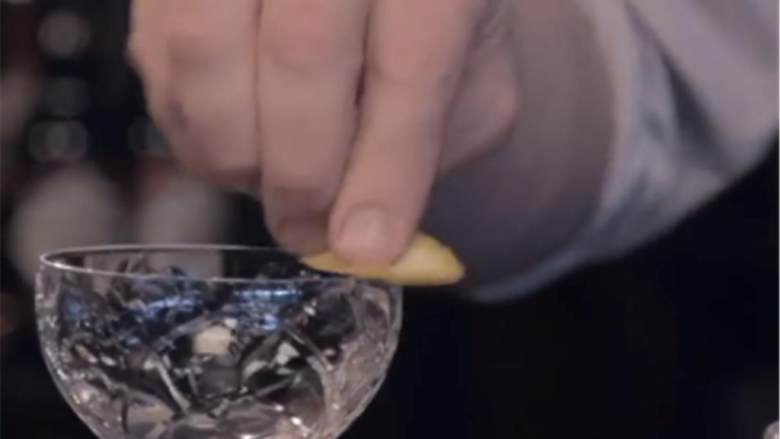 帝王的炼金药,把酒杯中的冰块倒出。在冰镇好的酒杯上挤上柠檬汁,把柠檬片放入酒杯中。