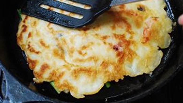 海鲜葱饼,煎到底部呈现金棕色(大约需要3-4分钟),翻面,再倒一些油,用锅铲压住,继续煎3-4分钟。