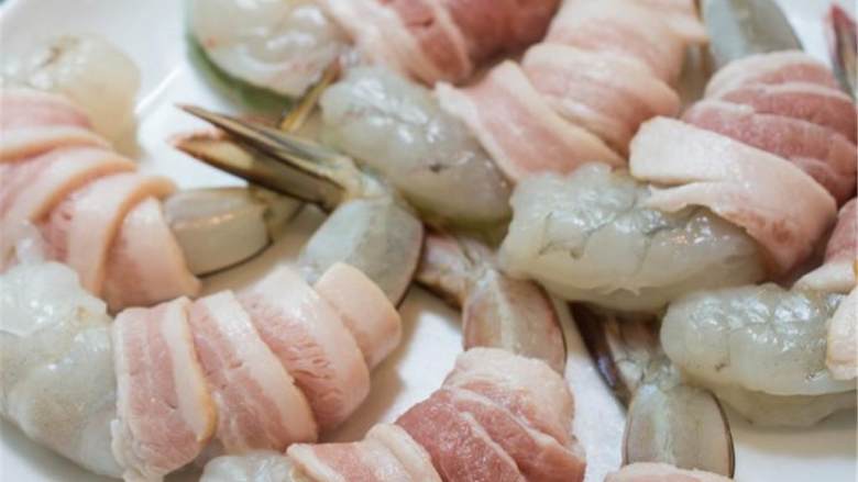 培根包虾仁,培根 纵向对半切开。总共得到了8片培根。大虾 去壳去肠，每一只都用一片培根包裹起来，两面撒上盐和黑胡椒调味。