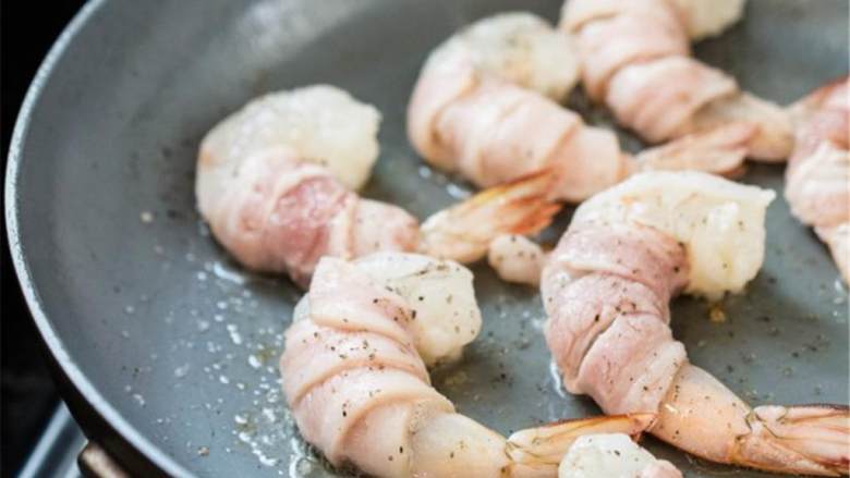 培根包虾仁,煎好后从锅中夹出，放在盘子上。