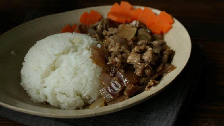 日式肥牛饭,米饭(2人份) 盛入碗里,把烧好的肥牛铺在米饭边上,摆好盘,浇上汤汁,然后用胡萝卜花装饰即可