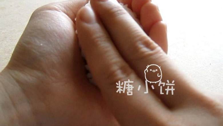 章鱼片握寿司,用另一只手的食指和中指按压表面,同时捏紧饭团。完成饭团坯.