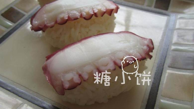 章鱼片握寿司,抹芥末膏的一面朝下,将章鱼切片覆盖在饭团上。芥末膏既杀菌调味,也起到了粘合饭团和顶料的作用.