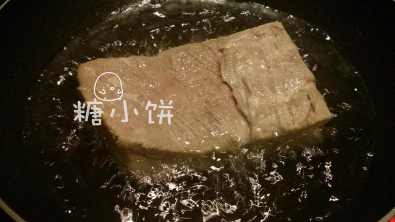 梅干菜扣肉(传统油炸版),宽锅热油,将五花肉 的肉皮朝下放入油锅中。油温以放入肉块的时候能冒出大泡为准.