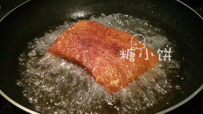 梅干菜扣肉(传统油炸版),盖上锅盖(这是为了防止被油爆到)炸至表皮金黄起泡后再翻面炸一会儿,至四周都上色的程度。