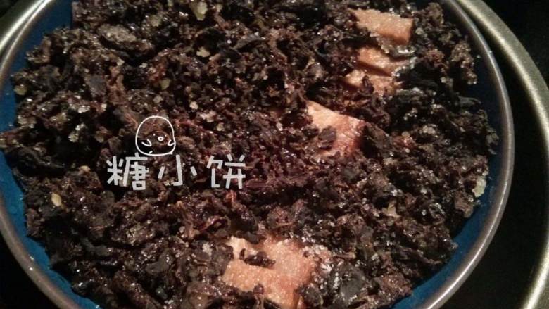 梅干菜扣肉(传统油炸版),梅干菜用清水冲洗一下,加剩余的白砂糖拌匀,铺在码好的肉片上面。