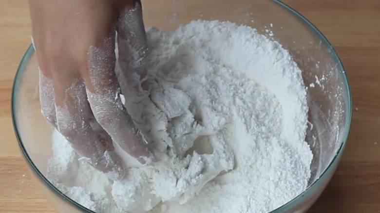 麻团,取一个大碗,混合剩下的糯米粉 、糖 、 泡打粉 ;把冷却好的小面团也放进去;慢慢地加入水 ,不断揉捏,直到形成光滑的面团。