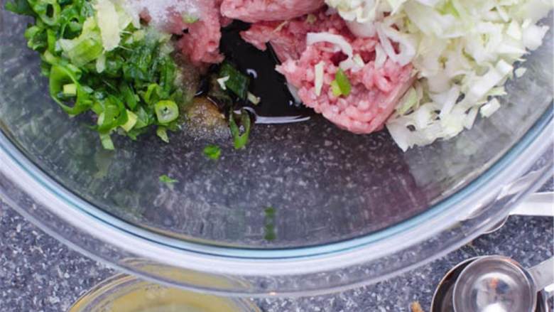 亚洲猪肉水饺,剥开并磨碎3厘米的一段生姜,在大碗里,将450克猪肉 、切碎的卷心菜 和切碎的香葱 混合在一起。