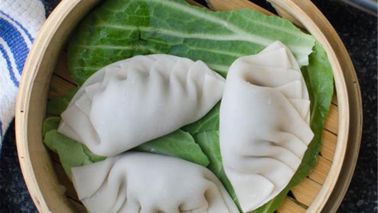 亚洲猪肉水饺,在一只大锅中加入足够的水烧开,在竹蒸笼上放几片卷心菜叶。